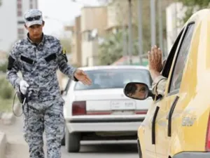 رجل شرطة عراقي يفحص السيارات التي تمر عبر نقطة تفتيش في بغداد 