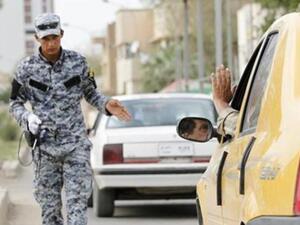 رجل شرطة عراقي يفحص السيارات التي تمر عبر نقطة تفتيش في بغداد 