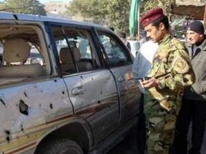 عناصر امن عراقيون يتفقدون سيارة تضررت جراء احد التفجيرات في بغداد