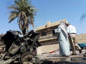 Iraqis look at the remains of a vehicle following an explosion on October 27, 2013, in the Mashtal district of the capital Baghdad. (Image credit: AFP)