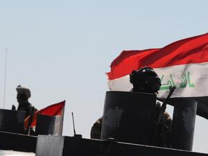 An Iraqi policeman in Ramadi sits on an armored vehicle mounted with a national flag on Feb. 12, 2016, after security forces retook the eastern outskirts of the city from Daesh. (AFP/Ahmad al-Rubaye)