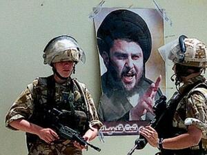 جنود من التحالف يقفون الى جوار صورة للصدر في بغداد