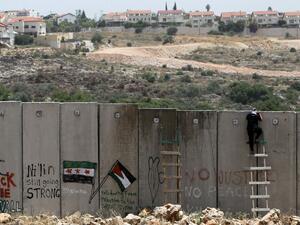 A Palestinian protester climbs Israel’s controversial separation barrier during clashes with Israeli security forces following a demonstration against Israeli settlements and its separation wall, in the West Bank village of Nilin near the Jewish settlement. (AFP/File)