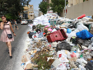 A woman holds her breath as she walks near a temporary garbage dump in the neighbourhood of Jdeideh, northeast of the Lebanese capital Beirut on September 1, 2016.
(ANWAR AMRO / AFP)