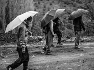 Xana going to school with his friends on a rainy day. Because his village does not have a junior high school, Xana must travel to school in the next village, seven kilometers, or about 4.3 miles, from home. (Photo credit: Arash Khamooshi)