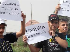 Palestinian refugees living in Jordan hold placards during a demonstration against the planned cuts in services related to the United Nations Relief and Works Agency (UNRWA)’s education program, August 5, 2015. [AFP]