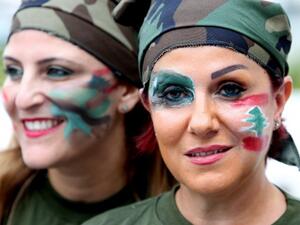 Lebanese women dressed in military fatigue and their faces painted with the colors of their national flag hold a sit in at Martyrs square in downtown Beirut, in support of the Lebanese army, on August 18, 2014. (AFP/Anwar Amro)