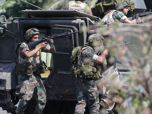 Lebanese Army soldiers take cover behind their armoured vehicle as they enter the Abra neighbourhood on the eastern outskirts of Sidon (Joseph Eid / AFP)