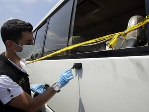 Lebanese policemen search for evidence at the site where at least twenty people were injured when masked assailants wielding knives attacked a bus in Beirut.(Joseph Eid / AFP)