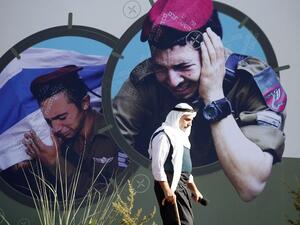 LEBANON, Aita Al-Shaab : Images of grieveing Israeli soldiers adorns a wall as a supporter of the Shiite Muslim Hezbollah movement walks past. AFP PHOTO / MAHMOUD ZAYYAT