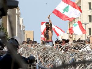 Lebanese protesters wave the national flag in front of a barbed wire fence as large crowds rally in Beirut on August 23, 2015. (Anwar Amro/ AFP)