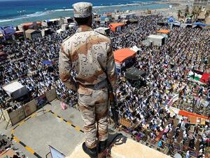 A Libyan rebel stands guard on top of a roof overlooking thousands performing noon prayers in Revolution Square in Benghazi on May 13, 2011. (Saeed Khan/ AFP)