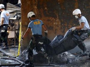شرطيان يحملان جثة احد ضحايا حريق بمصنع في مانيلا يوم الارربعاء

