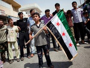 In August this year a boy holds a pre-Baath Syrian flag, that was adopted by the Syrian revolution during the uprising. (AFP PHOTO / ACHILLEAS ZAVALLIS)