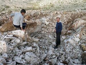 Syrian men stand inside a crater where they said a Scud missile landed near the military base of Sheikh Suleiman on the outskirts of the northwestern town of Darret Ezza on Friday. (AFP PHOTO / HERVE BAR)