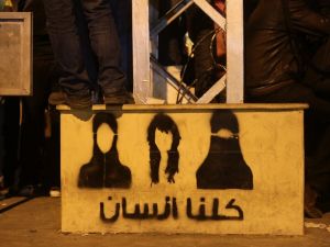 An opposition supporter stands on top of a step painted with graffiti and Arabic writing that reads, "We are all people" during a demonstration outside Egyptian presidential palace against Egyptian President Mohamed Morsi. (AFP PHOTO/PATRICK BAZ)