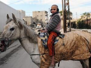 A Syrian child poses on a horse in the northern city of Aleppo. (AFP PHOTO/BULENT KILIC)