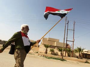 A man holds the Saddam-era national Iraqi flag as he walks in Tikrit. (AFP PHOTO/AHMAD AL-RUBAYE)