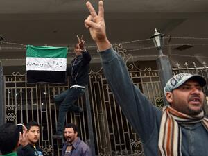 An Egyptian protestor flashes the sign for victory as he puts a flag with writing on it reading in Arabic: "state of Port Said" on the gate of the security headquarters, following the withdrawal of police forces from the main office. (AFP PHOTO / KHALED DESOUKI)