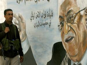 A Fatah movement member stands next to a mural of the Palestinian leader Mahmoud Abbas in the Ain al-Helweh Palestinian refugee camp on the outskirts of the southern Lebanese city of Sidon. (AFP PHOTO/MAHMOUD ZAYYAT)