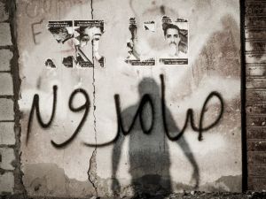 The shadow of a Bahraini protestor is seen over a graffiti which reads in Arabic "steadfast" during clashes with riot police following the funeral of Jaffar Jassim al-Taweel in the village of Sitra, south of Manama on March 27, 2013. 35-year-old Taweel died in the hospital after developing respiratory complications and according to his relatives is due to the inhalation of poisonous tear gas that riot police used during a protest in March 2013. (AFP PHOTO/MOHAMMED AL-SHAIKH)