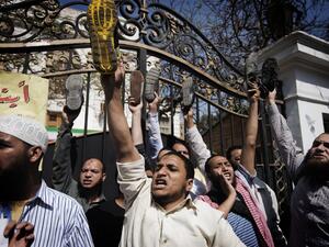 Egyptian protestors raise their shoes as they shout political and religious slogans outside the Iranian ambassador's residence in Cairo. (AFP PHOTO/GIANLUIGI GUERCIA)