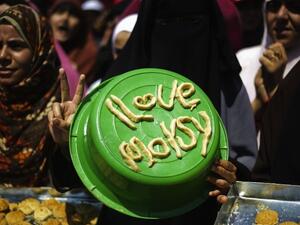 An Egyptian woman displays a pro-Morsi slogan made of pastry to be used for Eid al-Fitr cookies as supporters of ousted president Mohammed Morsi take part in a sit-in outside Cairo's Rabaa al-Adawiya mosque on August 7 (AFP)

