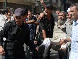 Egyptian policemen carry an Islamist man outside Cairo's Al-Fath mosque where Islamist supporters of ousted president Mohamed Morsi held up on August 17, 2013. (AFP)
