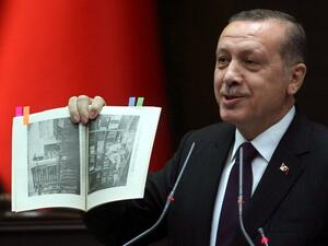 Turkish Prime Minister Recep Tayyip Erdogan shows a book from the Turkish Anthropology Institutes during an address to his ruling party. (AFP PHOTO / ADEM ALTAN)
