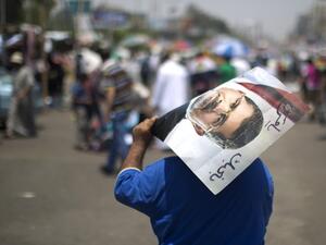 An Egyptian supporter of the Muslim Brotherhood walks holding a poster featuring deposed president Mohamed Morsi during a rally to support him on July 6 (Mahmud Hams / AFP)