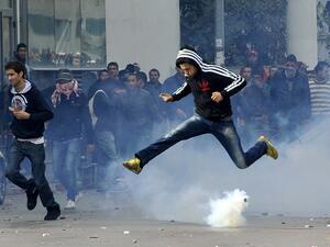 A Tunisian protester jumps amid smoke after police fired tear gas during a rally outside the Interior ministry to protest after Tunisian opposition leader and outspoken government critic Chokri Belaid was shot dead. AFP PHOTO / FETHI BELAID