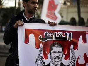 An Egyptian anti-government protester holds a poster mocking Egypt's President Mohamed Morsi during a demonstration outside the presidential palace in Cairo on February 8, 2013. [Getty Images]
