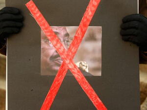 An activist holds a poster of Sudanese President Omar al-Bashir during a protest in front of the Sudanese Embassy in Washington, DC. (Getty)