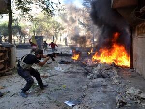 An opposition fighter aims fire as others run for cover while they hold a position behind burning tyres in the Salaheddin district of the northern Syrian city of Aleppo on October 9, 2013. (AFP)