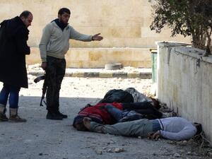 Rebel fighters gesture next to the bodies of handcuffed and blindfolded dead men laying on the ground of the Aleppo headquarters of the Islamic State of Iraq and the Levant earlier this month. (AFP/File)
