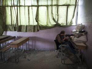A rebel fighter aims his weapon to Syrian government forces' positions inside a destroyed school in the Izaa district of Aleppo, on July 14, 2013. (AFP)