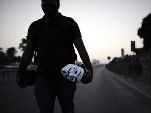 A Bahraini photographer holds a mask of Guy Fawkes used by the anonymous movement during an anti-government protest in the village of Bilad al-Qadeem, in a suburb of the capital Manama. (AFP)
