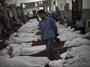An Egyptian man walks between lines of bodies wrapped in shrouds at a makeshift morgue in Cairo on August 15, 2013, following a crackdown on the protest camps of supporters of Mohamed Morsi. (AFP)