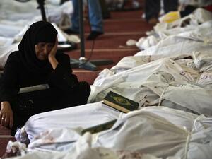 An Egyptian woman mourns over the body of her daughter wrapped in shrouds at a mosque in Cairo on August 15, 2013, following a crackdown on the protest camps of supporters of ousted Islamist president Mohamed Morsi the previous day. (AFP)