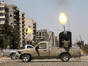 A Syrian rebel fires as a regime fighter jet flies overhead in Syria's eastern town of Deir Ezzor, on August 17, 2013. (AFP)