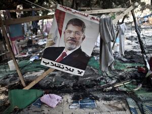 A picture of Egypt's ousted president Mohamed Morsi is seen hanging admist debris at Rabaa al-Adawiya square in Cairo on August 15, 2013, following a crackdown on the protest camps of supporters of the ousted Islamist leader the previous day. (AFP)