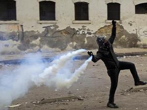 An Egyptian 'Black Bloc' protestor throws a tear gas canister toward a police line. (Facebook)