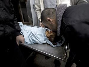 A relative of three-year-old Palestinian girl Hala Abu Sabikha kisses the forehead of the toddler as she lies in the morgue of the hospital in Deir al-Balah in the central Gaza Strip on December 24, 2013. (AFP)