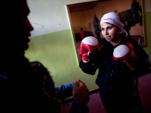An Afghani woman in a head scarf playing boxing.