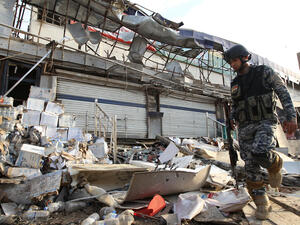 An Iraqi policeman inspects the damage outside a supermarket in central Baghdad's commercial Karrada neighbourhood on June 25, 2013 after a car bomb exploded in the parking area the night before. (Source: AFP/ALI AL-SAADI)