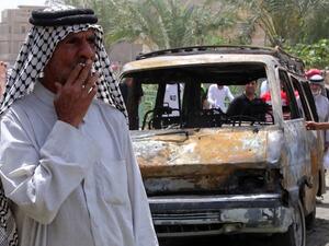An Iraqi man smokes a cigarette in front of a burnt vehicle at the site of a car bombing at a market in Baghdad's impoverished district of Sadr City. AFP Photo