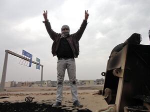 A man shows off the V-sign for victory as he stands on top of a burn out lorry on the side of the main highway leading west out of the capital Baghdad to Fallujah, on January 5, 2014. (AFP)
