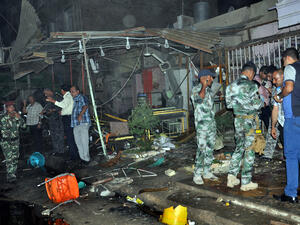 Iraqis and policemen gather at the scene of an explosion in Nasiriyah, south of the Iraqi capital Baghdad. (AFP/STR)