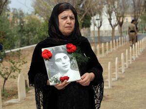 An Iraqi Kurdish woman visits the grave of her sister, who was killed in a gas attack by former Iraqi president Saddam Hussein in 1988 (AFP Photo)