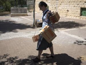An Israeli woman carries gas masks as she leaves the distribution centre in Jerusalem on August 26, 2013 (AFP)
